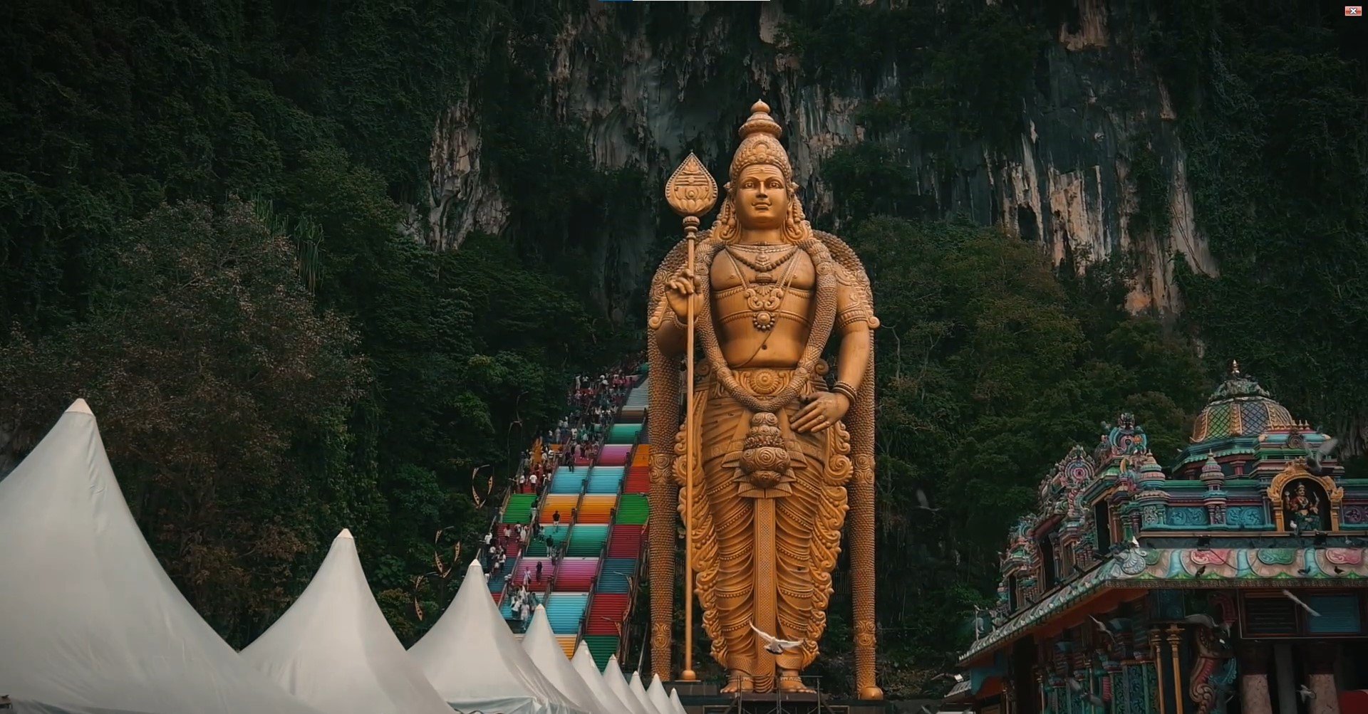 Colourful rainbow staircase leading up to the Batu Caves entrance with the golden Murugan statue on the left
