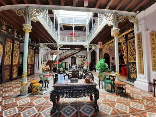 Ornate interior of Pinang Peranakan Mansion showing antique furniture and tile floors
